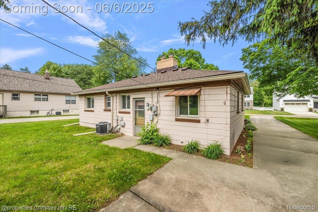 15501 Portis St, Northville, MI 48170 - rear view of house featuring central AC unit, a lawn, and a chimney