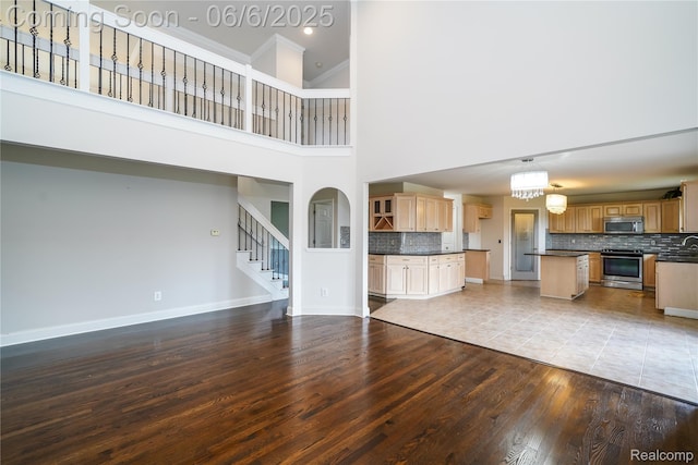 42105 Dorchester Ct, Clinton Township, MI 48038 - unfurnished living room with wood finished floors, stairway, baseboards, and a towering ceiling