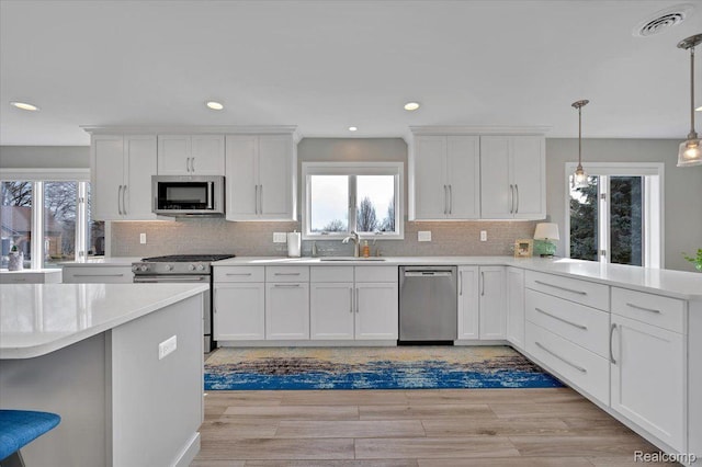 61381 Miriam Dr, Washington, MI 48094 - kitchen with appliances with stainless steel finishes, white cabinets, light countertops, tasteful backsplash, and a peninsula