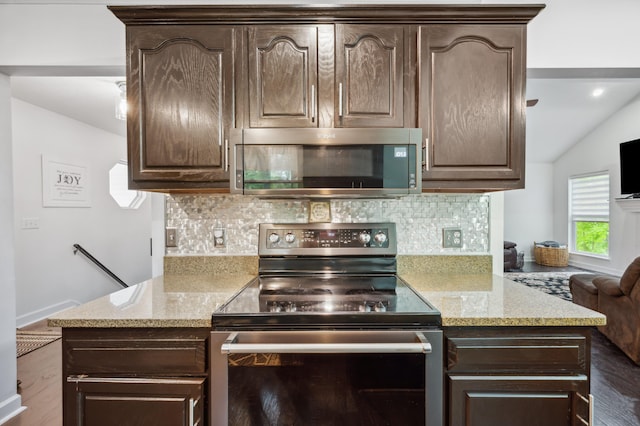 4085 Ravina Ter, Saint Joseph, MI 49085 - kitchen featuring stainless steel appliances, dark brown cabinetry, tasteful backsplash, vaulted ceiling, and light stone countertops