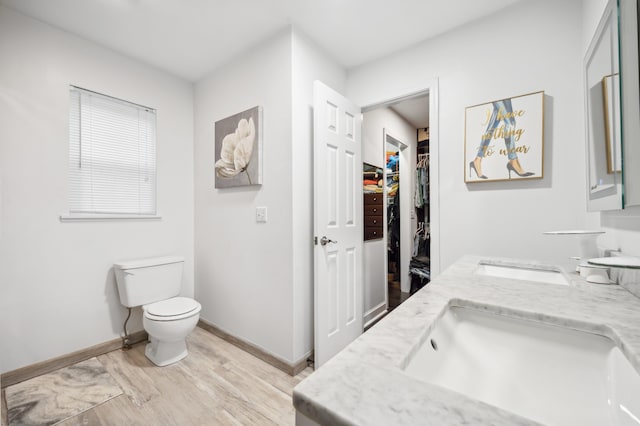 4085 Ravina Ter, Saint Joseph, MI 49085 - bathroom featuring wood finished floors, toilet, double vanity, baseboards, and a walk in closet
