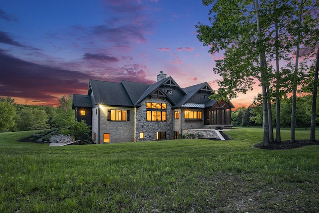 4035 136th Ave, Hamilton, MI 49419 - back of property at dusk with a chimney, a yard, a standing seam roof, stone siding, and metal roof