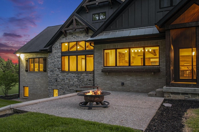 4035 136th Ave, Hamilton, MI 49419 - rear view of house featuring a fire pit, a patio, board and batten siding, and stone siding