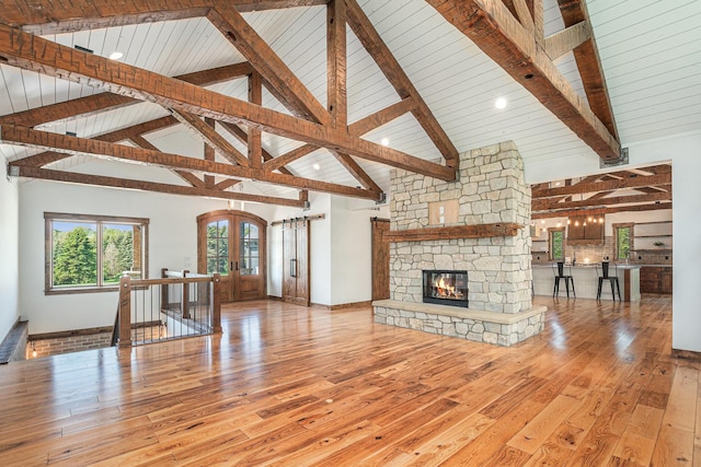 4035 136th Ave, Hamilton, MI 49419 - unfurnished living room featuring french doors, hardwood / wood-style flooring, a stone fireplace, wooden ceiling with exposed beams, and high vaulted ceiling