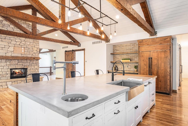 4035 136th Ave, Hamilton, MI 49419 - kitchen featuring a barn door, a sink, open floor plan, an island with sink, and light wood-style floors