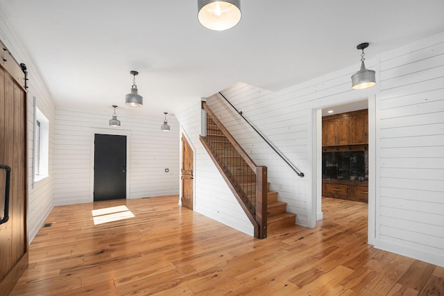 4035 136th Ave, Hamilton, MI 49419 - foyer entrance with wooden walls, stairway, light wood-style floors, and a barn door
