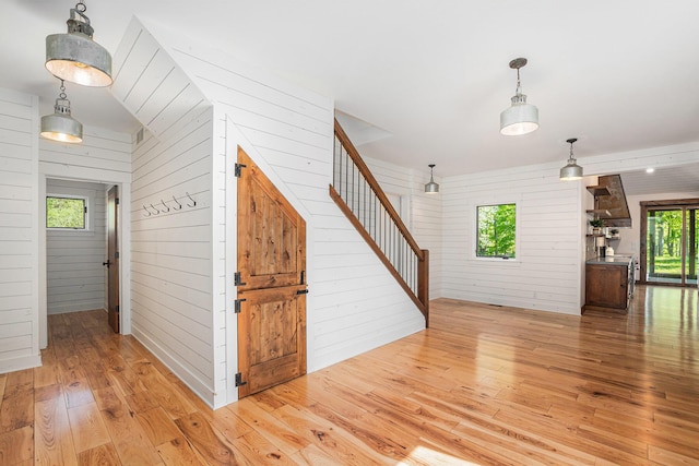 4035 136th Ave, Hamilton, MI 49419 - unfurnished living room featuring light wood-style flooring, wood walls, and stairs
