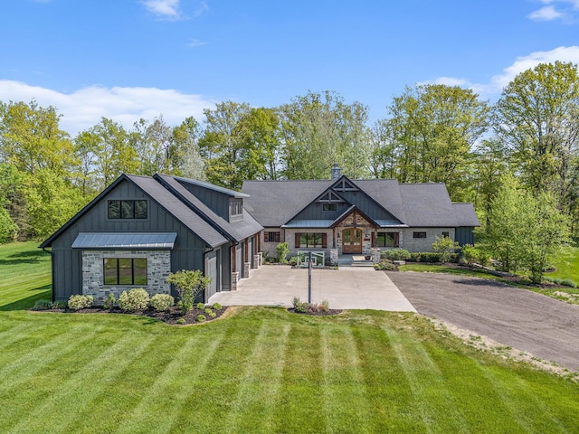 4035 136th Ave, Hamilton, MI 49419 - view of front of house featuring board and batten siding, concrete driveway, a front yard, stone siding, and a chimney