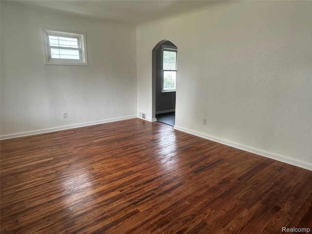 23767 Battelle Ave, Royal Oak, MI 48030 - empty room featuring arched walkways, healthy amount of natural light, dark wood finished floors, and baseboards