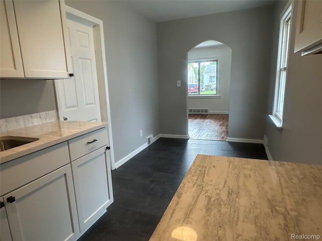 23767 Battelle Ave, Royal Oak, MI 48030 - kitchen featuring arched walkways, white cabinets, light stone counters, and baseboards