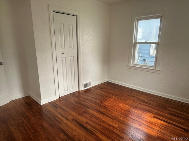 23767 Battelle Ave, Royal Oak, MI 48030 - unfurnished bedroom featuring dark wood-type flooring, baseboards, a closet, and a textured wall