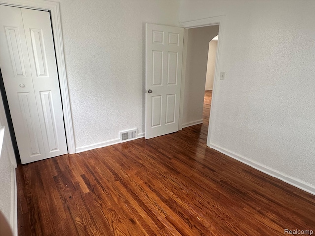 23767 Battelle Ave, Royal Oak, MI 48030 - unfurnished bedroom featuring arched walkways, wood finished floors, a closet, baseboards, and a textured wall