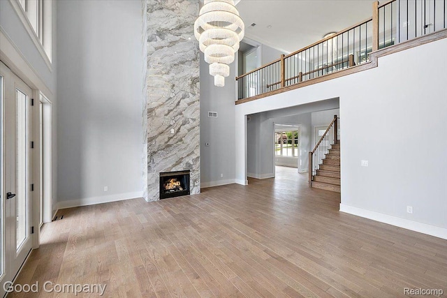 1760 Hamilton Dr, Bloomfield Hills, MI 48302 - unfurnished living room with a towering ceiling, a chandelier, a large fireplace, stairs, and wood finished floors