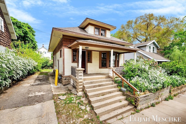 621 Olympia St SW, Grand Rapids, MI 49503 - view of front facade featuring covered porch, a shingled roof, and driveway