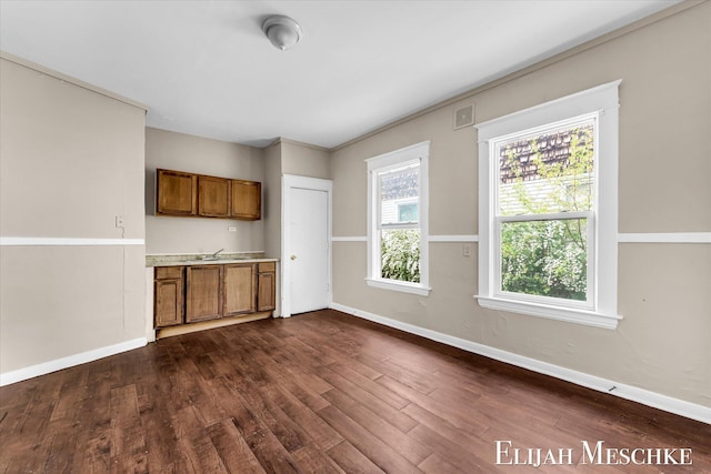 621 Olympia St SW, Grand Rapids, MI 49503 - kitchen with brown cabinets, dark wood-style flooring, baseboards, light countertops, and a sink
