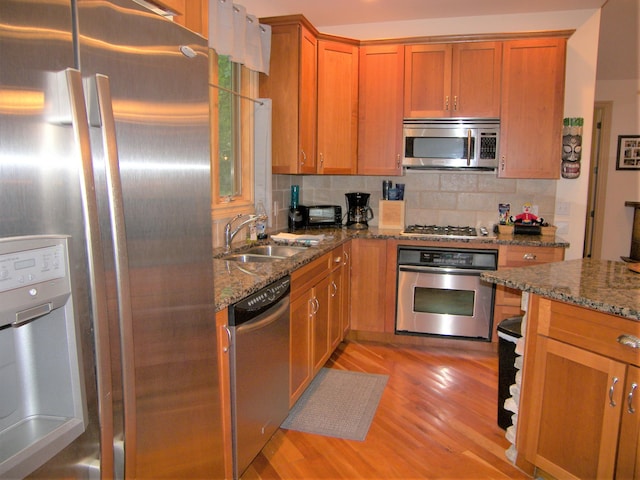 18774 Old Field Rd, New Buffalo, MI 49117 - kitchen featuring appliances with stainless steel finishes, a sink, light wood finished floors, backsplash, and dark stone countertops