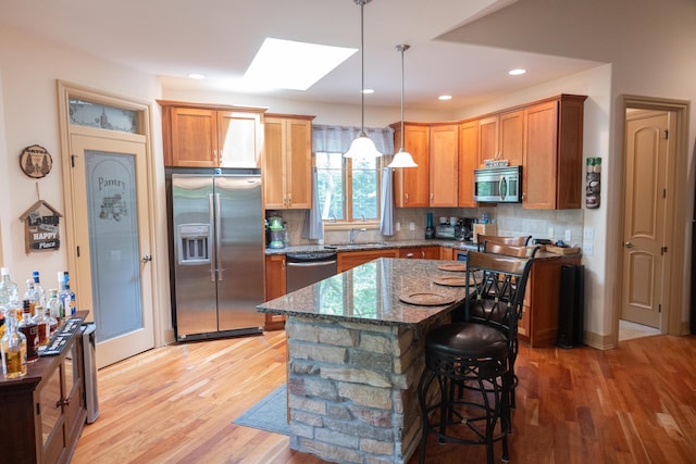 18774 Old Field Rd, New Buffalo, MI 49117 - kitchen with appliances with stainless steel finishes, a sink, light wood finished floors, a skylight, and backsplash