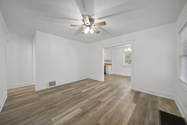 130 N Horton St, Jackson, MI 49202 - empty room featuring ceiling fan, wood finished floors, a chandelier, and baseboards