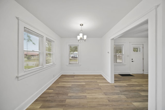 130 N Horton St, Jackson, MI 49202 - unfurnished dining area with a chandelier, baseboards, and wood finished floors