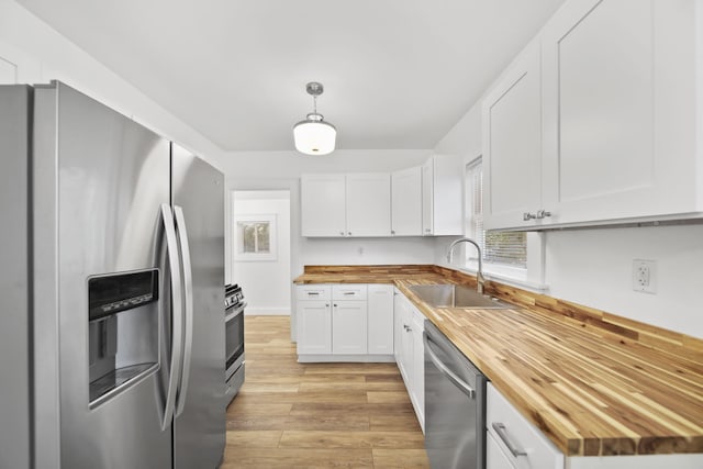 130 N Horton St, Jackson, MI 49202 - kitchen featuring butcher block counters, stainless steel appliances, a sink, light wood-style floors, and white cabinetry