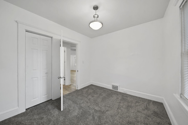 130 N Horton St, Jackson, MI 49202 - unfurnished bedroom with dark colored carpet, baseboards, and a closet