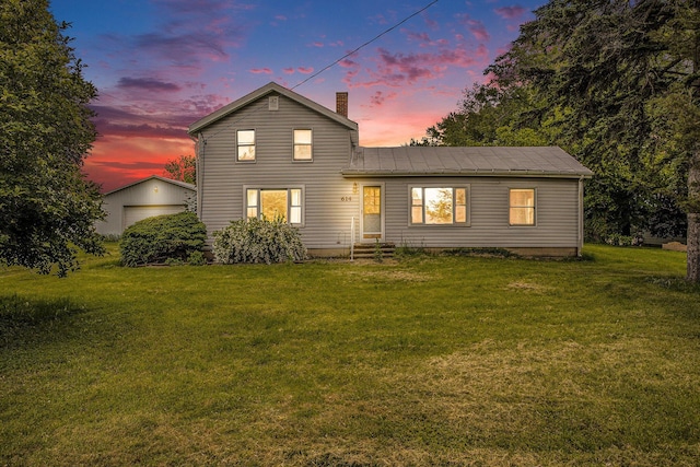 614 Marshall Rd, Coldwater, MI 49036 - back of house at dusk with a yard, a chimney, an outbuilding, entry steps, and metal roof