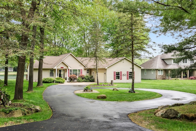 9228 Main St, Canadian Lakes, MI 49346 - ranch-style house featuring curved driveway, a front yard, a garage, and roof with shingles