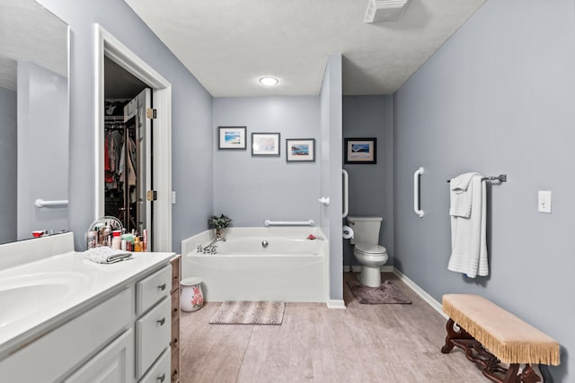 9228 Main St, Canadian Lakes, MI 49346 - full bathroom featuring vanity, a garden tub, wood finished floors, toilet, and a walk in closet