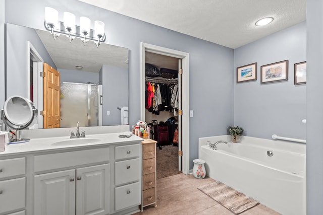 9228 Main St, Canadian Lakes, MI 49346 - full bathroom with vanity, a stall shower, a garden tub, a spacious closet, and a textured ceiling