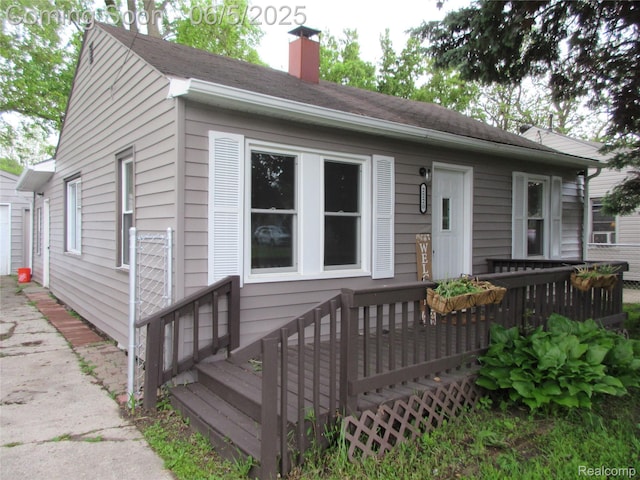2220 E Bergin Ave, Burton, MI 48529 - view of front facade featuring a wooden deck, a chimney, a garage, and driveway