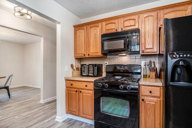 13860 Rolling Creek Dr, Lowell, MI 49331 - kitchen featuring black appliances, tasteful backsplash, light countertops, light wood finished floors, and a textured ceiling