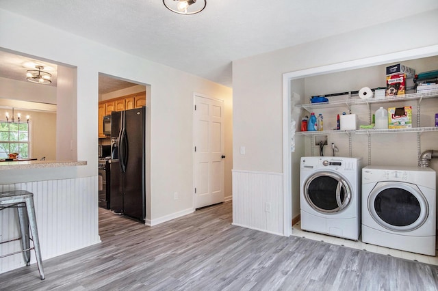 13860 Rolling Creek Dr, Lowell, MI 49331 - laundry area with washer and clothes dryer, a chandelier, light wood finished floors, and a wainscoted wall