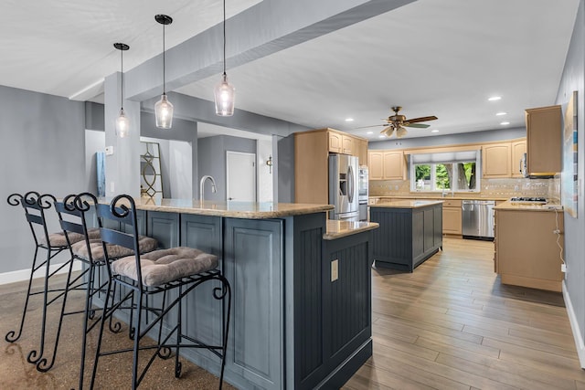 1102 S Durand St, Jackson, MI 49203 - kitchen with stainless steel appliances, a kitchen island, a breakfast bar area, decorative backsplash, and a ceiling fan