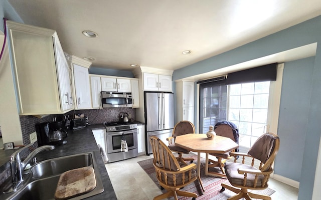 617 Stoll Rd, Lansing, MI 48917 - kitchen featuring stainless steel appliances, a sink, dark countertops, decorative backsplash, and white cabinetry