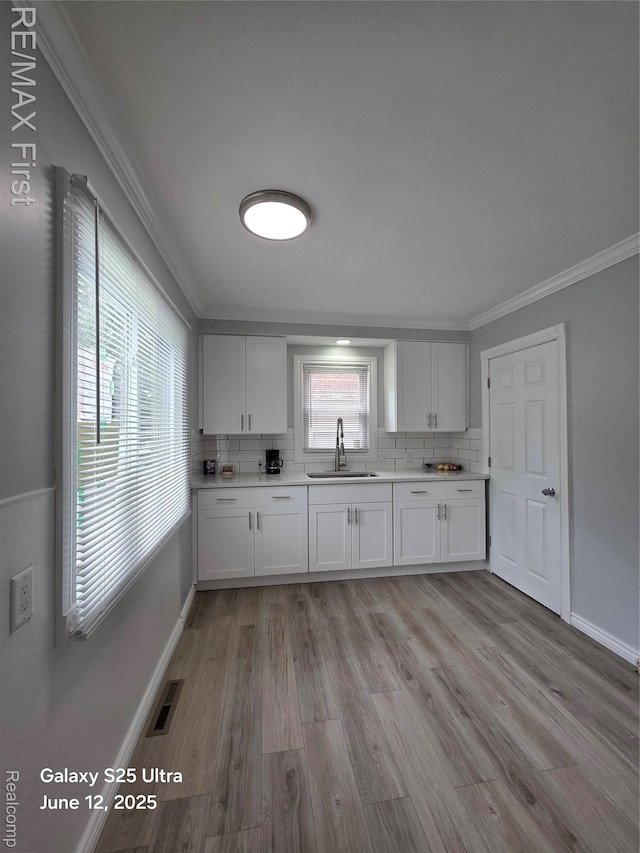 12725 Riverview St, Detroit, MI 48223 - kitchen with ornamental molding, decorative backsplash, light wood-style flooring, healthy amount of natural light, and light countertops