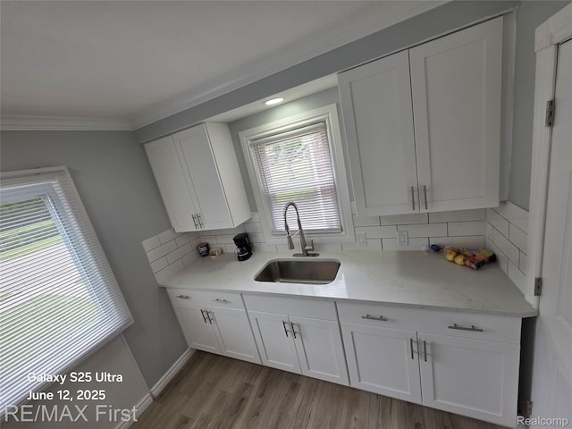 12725 Riverview St, Detroit, MI 48223 - kitchen with white cabinetry, tasteful backsplash, crown molding, light wood-style floors, and light stone countertops