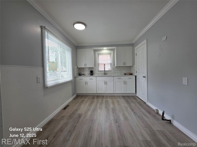 12725 Riverview St, Detroit, MI 48223 - kitchen with crown molding, light wood-style floors, white cabinetry, tasteful backsplash, and light countertops