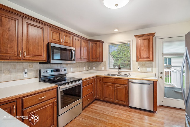 6063 Steeplechase Dr, Grand Blanc, MI 48439 - kitchen with appliances with stainless steel finishes, a sink, brown cabinets, light wood finished floors, and recessed lighting
