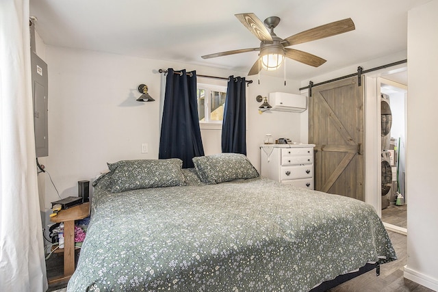 418 W Fargo St, Ionia, MI 48846 - bedroom with stacked washing machine and dryer, a barn door, electric panel, wood finished floors, and a wall unit AC