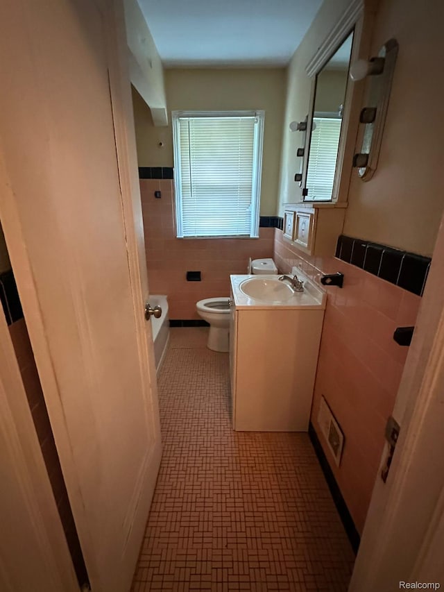 20258 Fairport St, Detroit, MI 48205 - bathroom featuring tile walls, toilet, vanity, and a wainscoted wall