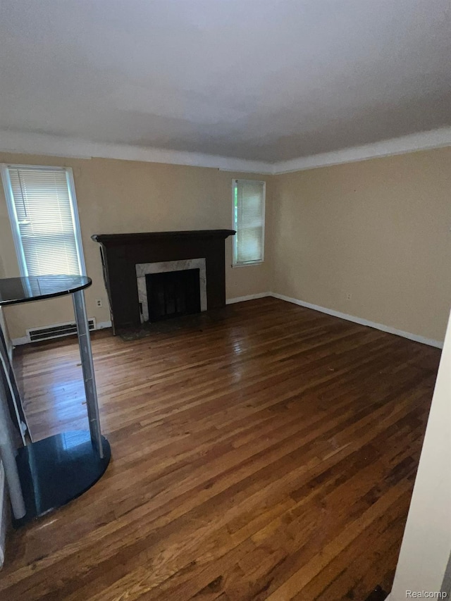 20258 Fairport St, Detroit, MI 48205 - unfurnished living room featuring dark wood-type flooring, baseboard heating, a high end fireplace, ornamental molding, and baseboards