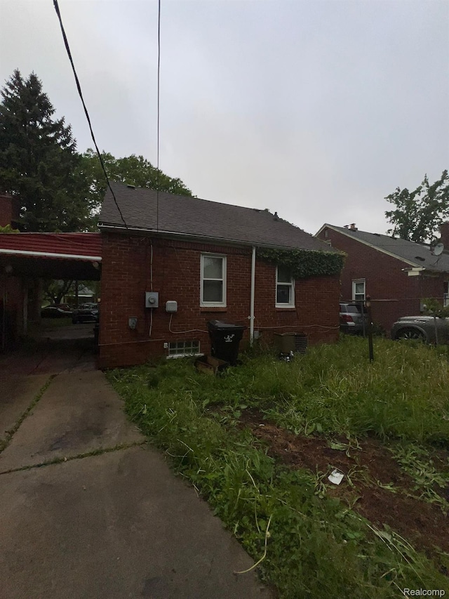 20258 Fairport St, Detroit, MI 48205 - view of property exterior featuring brick siding, an attached carport, driveway, and central air condition unit
