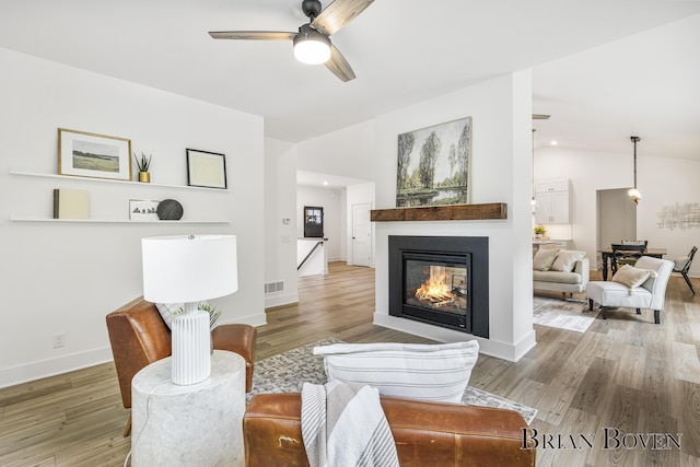 4846 Honeycrisp Dr NE, Rockford, MI 49341 - living room featuring ceiling fan, light wood-type flooring, a multi sided fireplace, baseboards, and vaulted ceiling