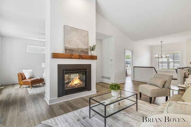4846 Honeycrisp Dr NE, Rockford, MI 49341 - living room featuring a chandelier, a multi sided fireplace, wood finished floors, baseboards, and high vaulted ceiling