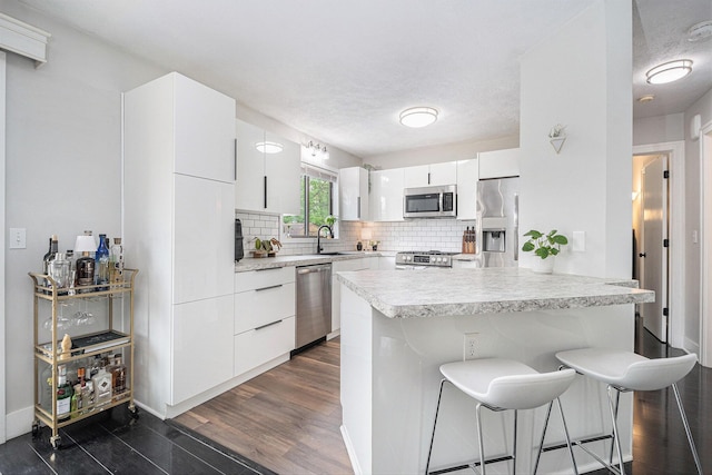 3360 Brook Trl SE, Grand Rapids, MI 49508 - kitchen with stainless steel appliances, a kitchen breakfast bar, backsplash, light countertops, and a sink