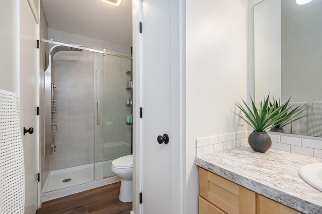 3360 Brook Trl SE, Grand Rapids, MI 49508 - bathroom with vanity, a stall shower, toilet, wood finished floors, and decorative backsplash
