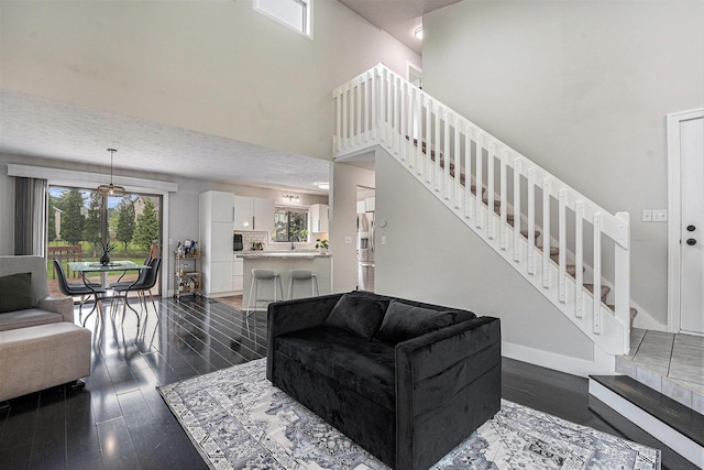 3360 Brook Trl SE, Grand Rapids, MI 49508 - living area with stairs, a towering ceiling, dark wood-type flooring, and baseboards