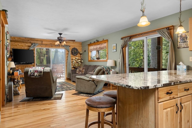376 Highview Rd, Traverse City, MI 49696 - kitchen featuring open floor plan, light wood-style floors, a ceiling fan, light stone countertops, and a kitchen breakfast bar