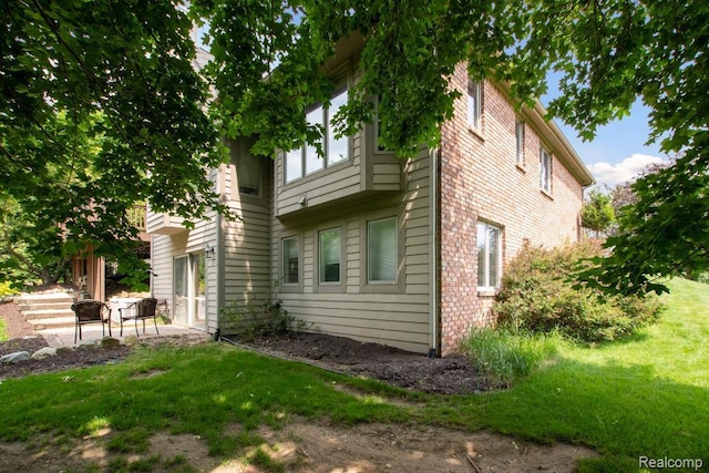 3468 High Hillcrest Dr, Howell, MI 48843 - view of home's exterior featuring a patio, a lawn, and brick siding