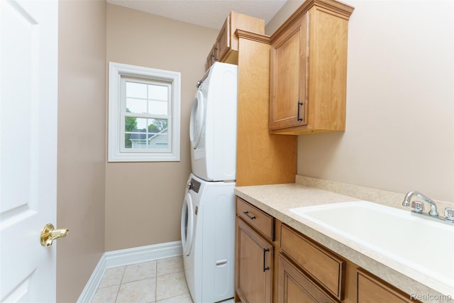 1235 Joann Ln, Williamston, MI 48895 - laundry room with estacked washer and dryer, cabinet space, light tile patterned floors, and baseboards